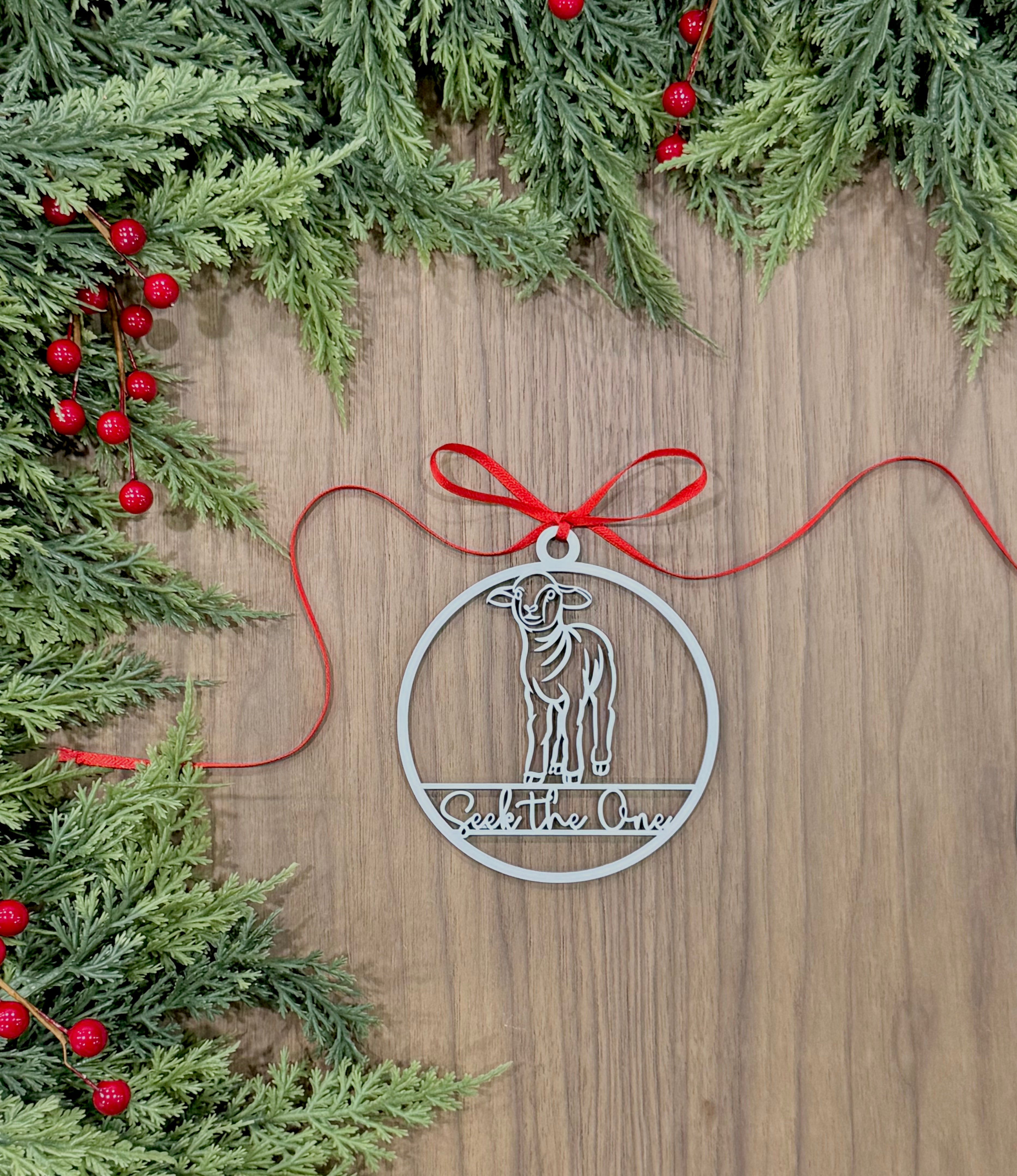 Decorative metal ornament with a goat design on a wooden surface with Christmas greenery.