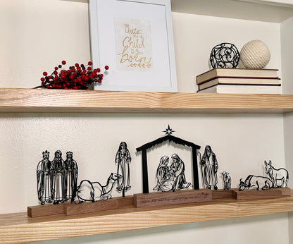 Nativity scene display on a wooden shelf with decorative items.