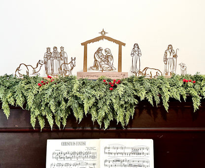 Decorative Christmas display with nativity scene, garland, and sheet music on top of a piano.