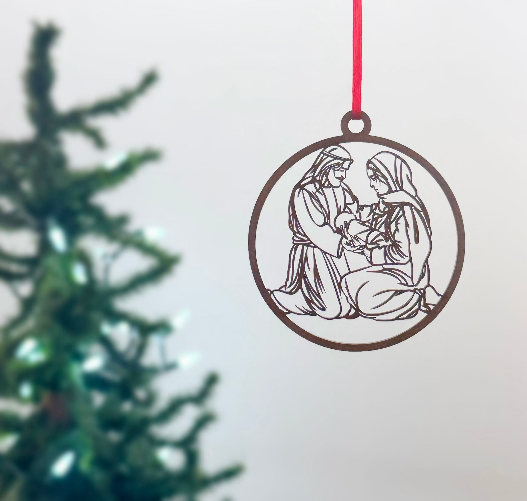 Decorative Christmas ornament with a religious scene on a white background with a pine tree.