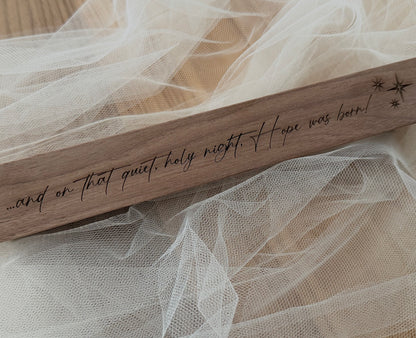 Wooden plaque with engraved text on a delicate fabric background