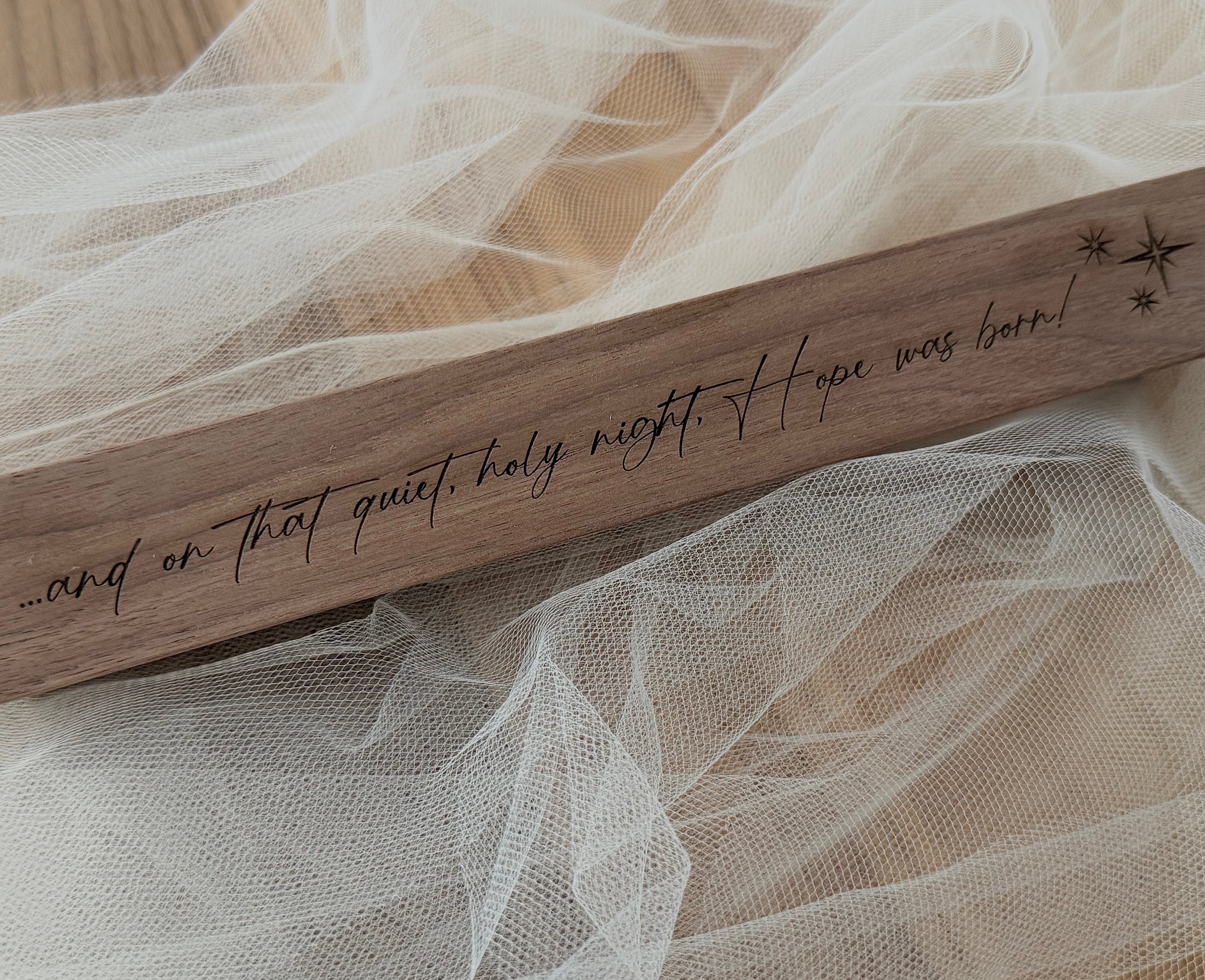 Wooden plaque with engraved text on a delicate fabric background