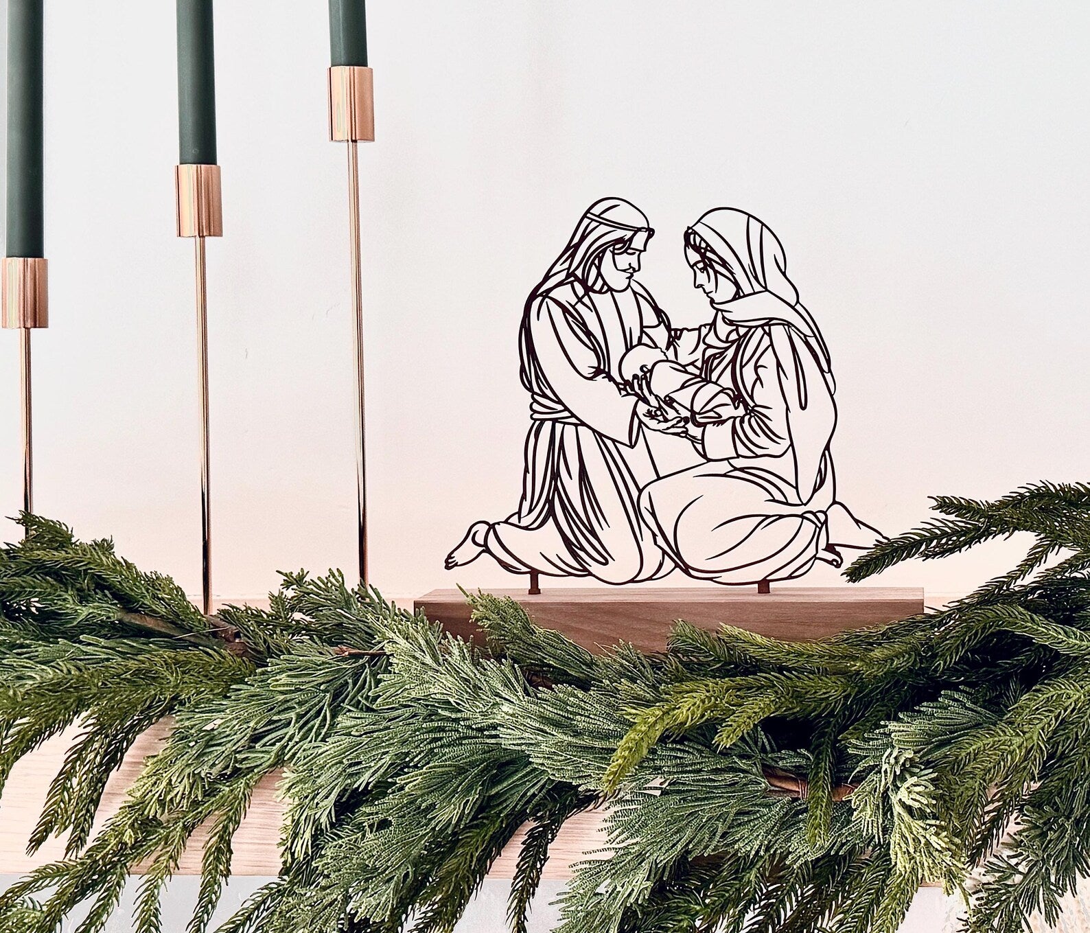 Decorative cutout of a religious scene with greenery and candles on a white background