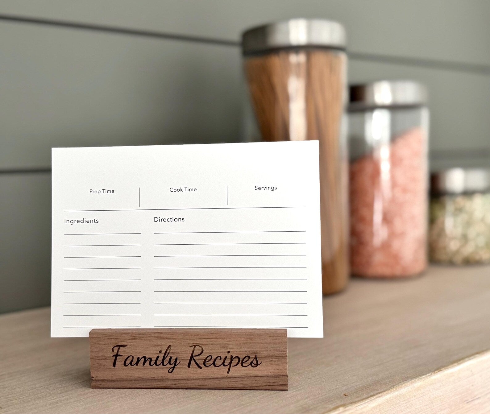 Recipe card on a wooden stand with 'Family Recipes' text, placed on a surface with jars in the background.